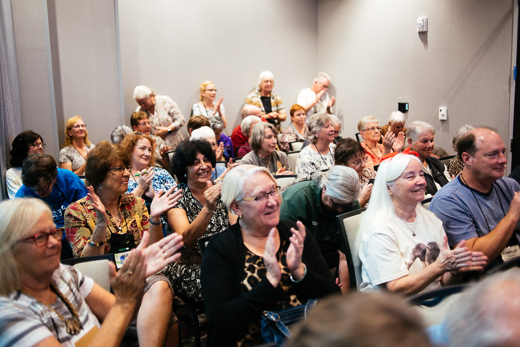 Group of AZADV members sitting together in a room clapping